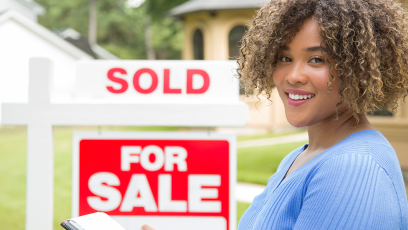 realtor in front of for sale sign with sold placard