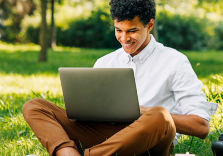 student studying outside on campus with laptop