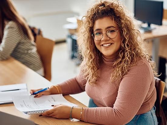 smiling student holding notebook and pen