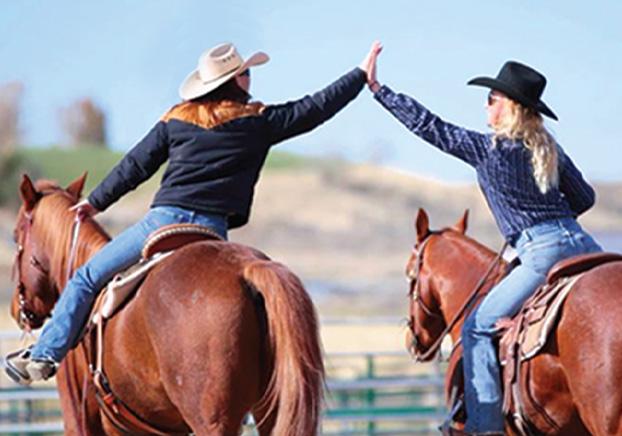 two horse riders touching hands in a high-five